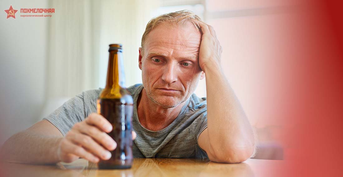 Мужчина смотрит на бутылку алкоголя